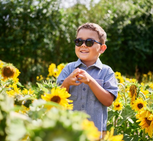 Kind met Milo & Me zonnebril tussen zonnebloemen